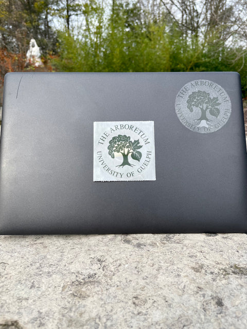 7.62 cm (Three inch) round, clear sticker with green writing which says "The Arboretum, University of Guelph" and includes The Arboretum's logo in the middle. 